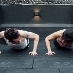 Two adults doing push-ups in an indoor gym setting in Mexico City, promoting a fit and healthy lifestyle.